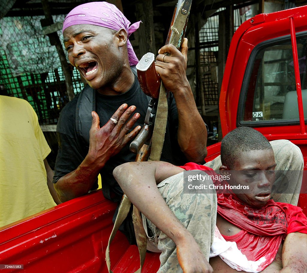 A government loyalist soldier grieves as a comrade dies of wounds suffered during a battle near front line positions August 2, 2003 in Monrovia, Liberia.